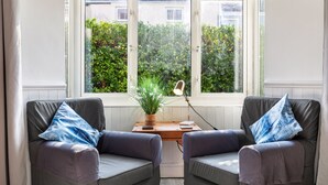 A room with two grey armchairs, a wooden table, and a potted plant.