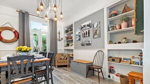 A dining area with a wooden table and chairs, a bench, and a bookshelf with various items.