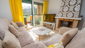 Ein Wohnzimmer mit einer Sofagarnitur, einem Couchtisch, einem Fernseher und einem Kamin.