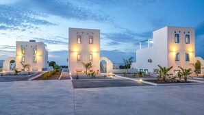 Un hotel moderno con un patio amplio, varias construcciones con arquitectura uniforme y ventanas bien iluminadas.