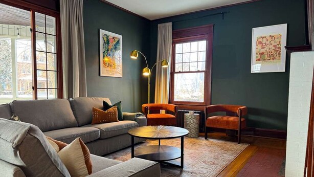 Ein Wohnzimmer mit einer Couch, Sesseln, einem Couchtisch und Kunstwerken an den Wänden.