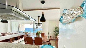 A modern kitchen with a view of the ocean, a dining area with a table and chairs, and a living area with a sofa and a large window. - 3 Bedrooms At Marbella Beachfront Juan Dolio No820 (Guayacanes)