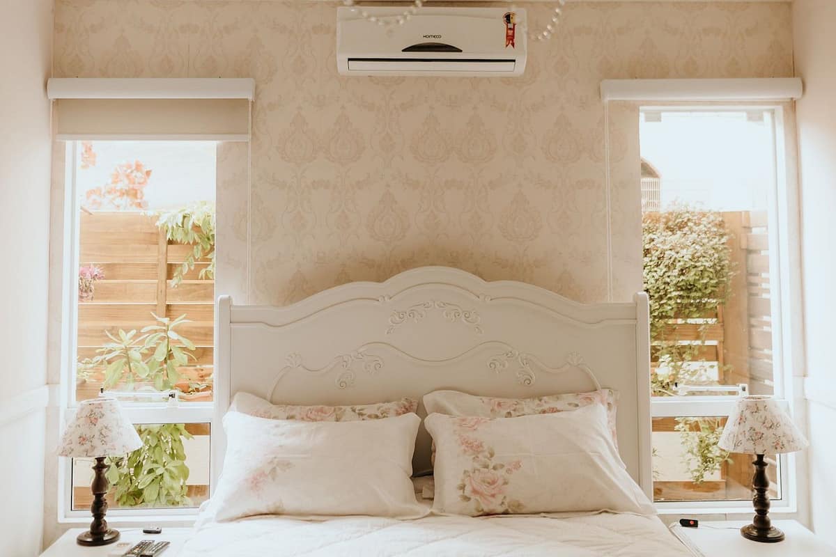 A bedroom with a white bed, floral bedding, a chandelier, and two bedside tables with lamps.