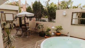 A wooden deck with a hot tub, outdoor seating, and potted plants. - Paty's Garden (Florianópolis)