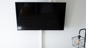 Una kitchenette equipada con microondas, refrigerador y televisor de pantalla plana montado en la pared.