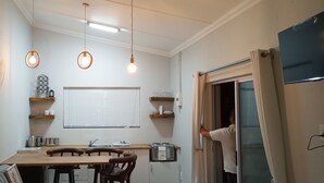 A compact kitchen with a dining table, chairs, a built-in oven, and a window with blinds.