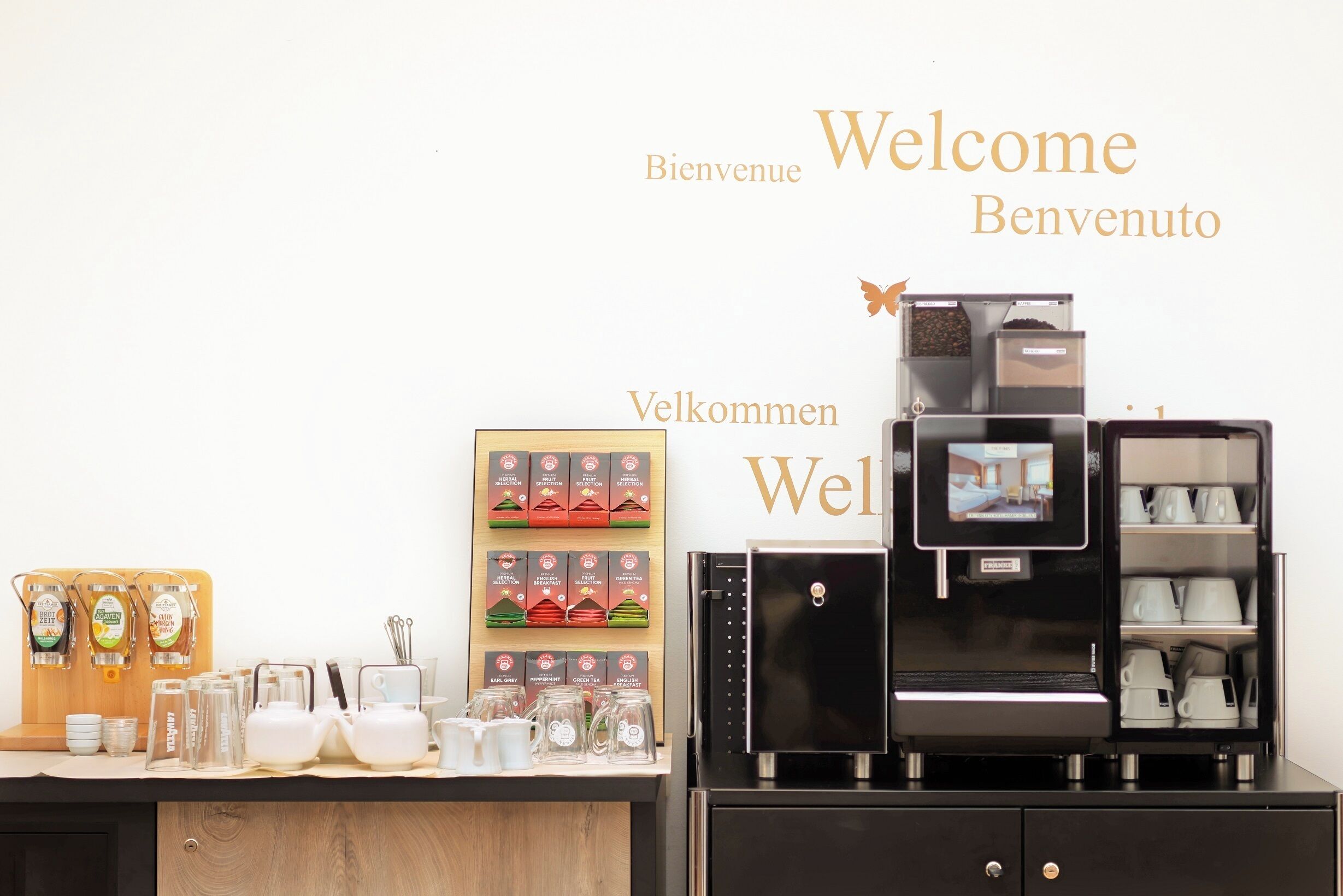 Un espace dédié au café, équipé d’une machine à café, de tasses et d’un présentoir de dosettes de café.