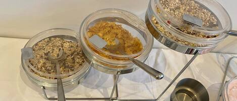 Tres recipientes de vidrio con soportes metálicos sobre una mesa, conteniendo distintos tipos de copos de cereales.