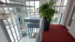 A modern interior with a red carpet, glass doors, and a potted plant. - Trip Inn Düsseldorf Neuss (Neuss)