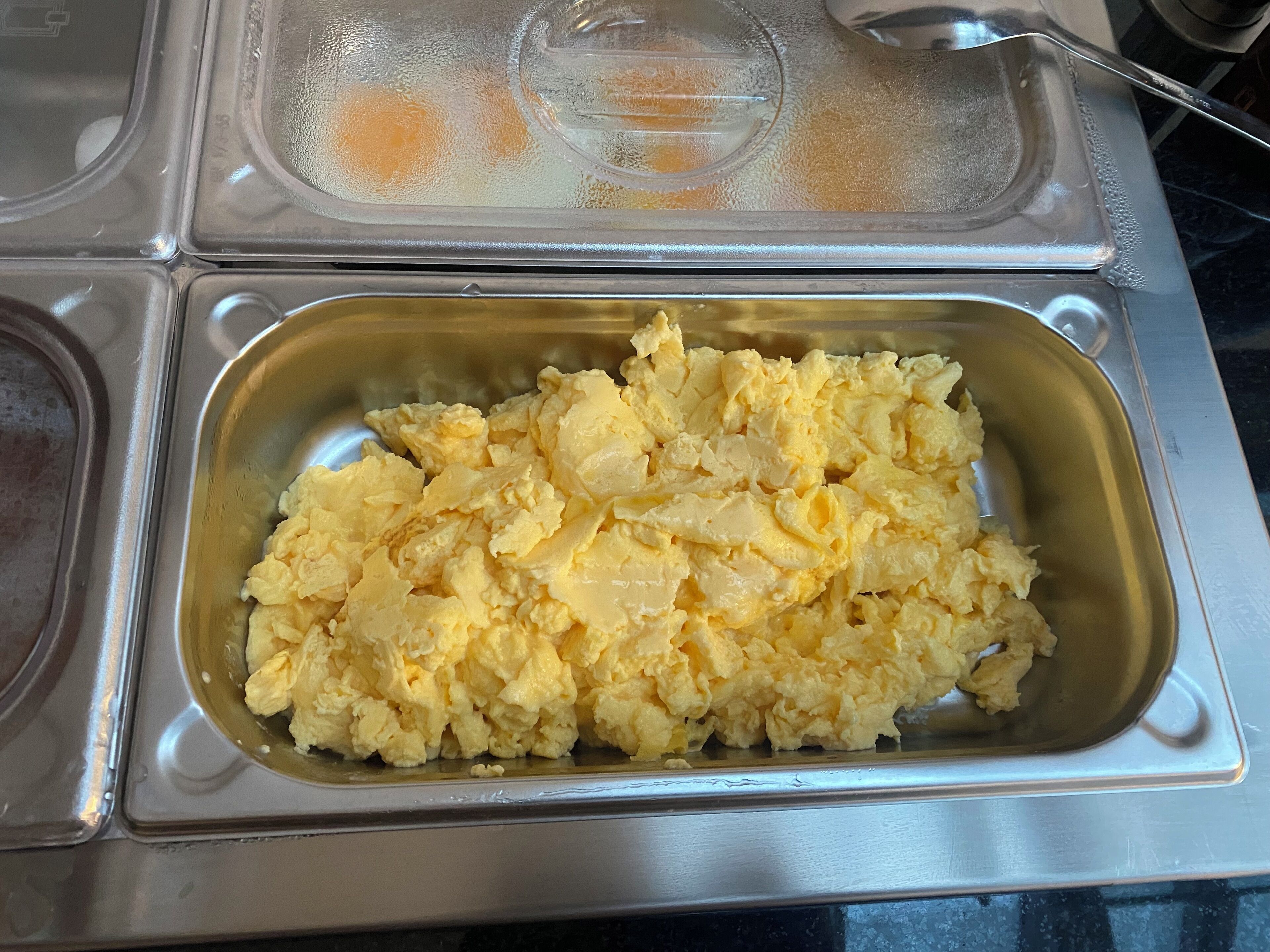Bandeja de acero inoxidable con huevos revueltos.