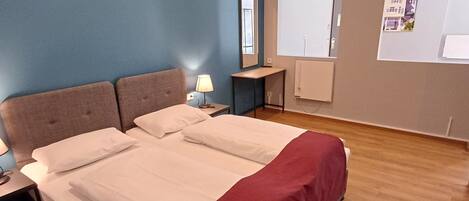 Una habitación de hotel con una cama grande, una mesita de noche, una lámpara, una ventana con vistas y un calefactor en la pared.