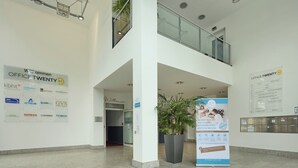 A modern hotel lobby with a high ceiling, multiple light fixtures, a glass railing on the upper level, and a large sign advertising the hotel. - Trip Inn Düsseldorf Neuss (Neuss)