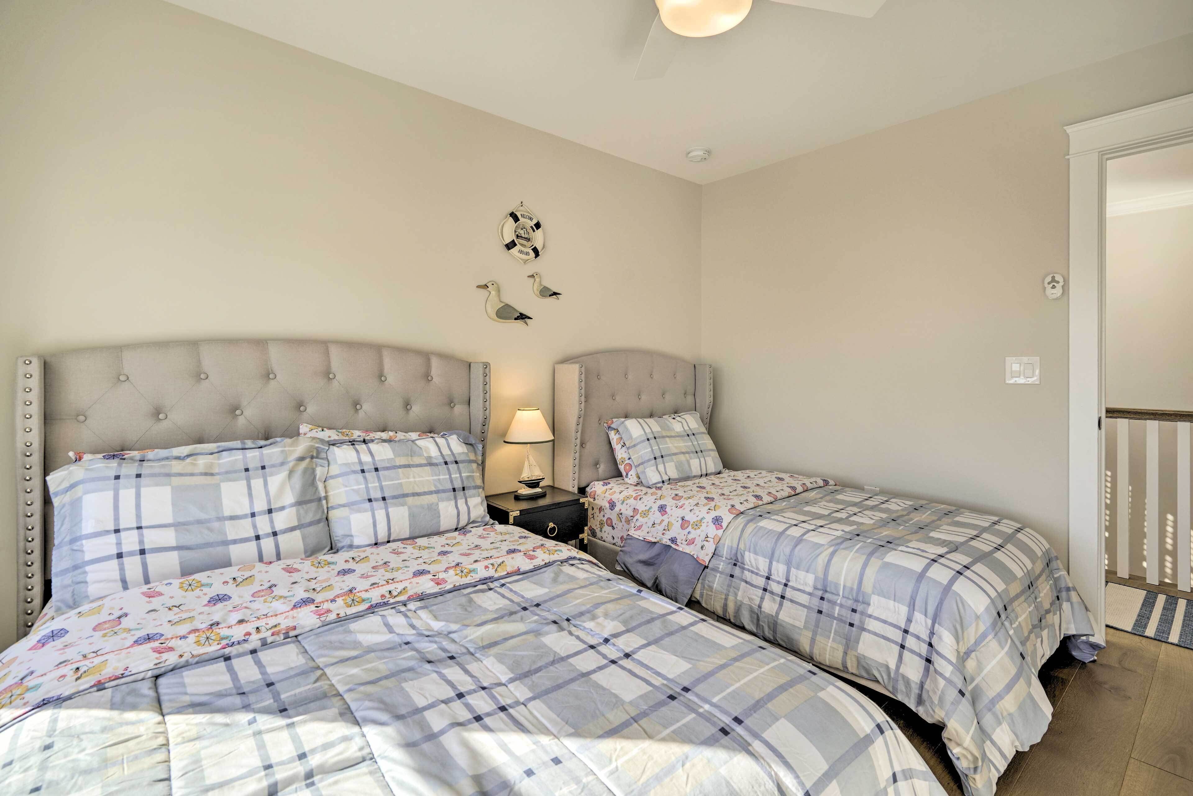 Une chambre avec deux lits, chacun doté d’une tête de lit capitonnée et d’une parure de lit assortie. Une table de chevet avec une lampe se trouve entre les deux lits.