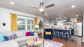 A modern living room with a sofa, coffee table, and a kitchen area with bar stools.