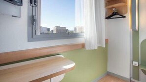 A room with a window, a wooden bench, a green wall, and a hanging black hanger.