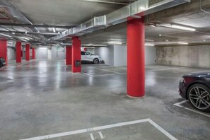 Eine mehrgeschossige Parkgarage mit roten Säulen, Betonböden und markierten Parkplätzen.