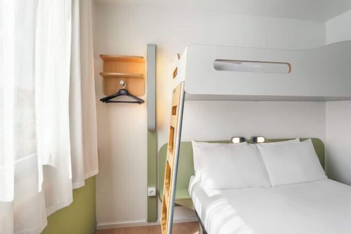 Ein Zimmer mit einem Einzelbett, einem Kopfteil, einem Nachttisch und einer Pendelleuchte.