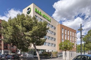 Un bed and breakfast con facciata moderna, un parcheggio e cielo sereno.