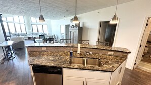 A modern kitchen with granite countertops, stainless steel appliances, and pendant lighting. - Brooklyn Bridge Vacation Condo (Arnolds Park)