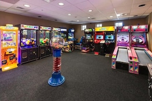 Una habitación con varias máquinas de arcade, incluyendo máquinas de garra y juegos de carreras, dispuestas en fila.
