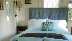 A bedroom with a bed, a chair, a lamp, and a floral-patterned carpet. - Little Red Caboose with a View in the Scenic Columbia River Gorge (Troutdale)