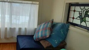 A room with a bed, a window with sheer curtains, and a stained glass window on the wall. - Little Red Caboose with a View in the Scenic Columbia River Gorge (Troutdale)