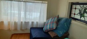 A room with a bed, a window with sheer curtains, and a stained glass window on the wall. - Little Red Caboose with a View in the Scenic Columbia River Gorge (Troutdale)
