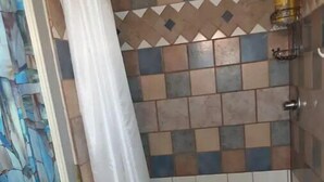 A shower area with a tiled wall, a showerhead, and a curtain. - Little Red Caboose with a View in the Scenic Columbia River Gorge (Troutdale)
