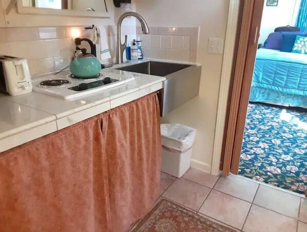 A compact kitchen with a sink, a kettle, and a trash bin. - Little Red Caboose with a View in the Scenic Columbia River Gorge (Troutdale)