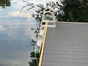 A wooden deck with a metal ladder leading to a roof.