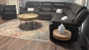 Ein modernes Wohnzimmer mit einer Eckcouch, zwei runden Couchtischen und einem gemusterten Teppich.