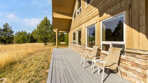 Una casa de madera con terraza, detalles de piedra y sillas de mimbre.