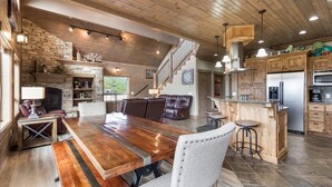 Un amplio salón con una mesa de comedor de madera, asientos de cuero y una chimenea de piedra.