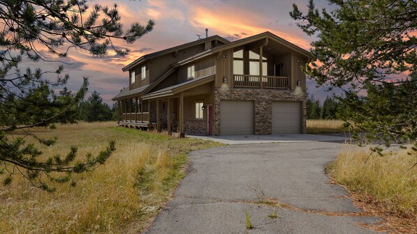 Une maison à deux étages avec une façade en pierre, un porche couvert et un garage.