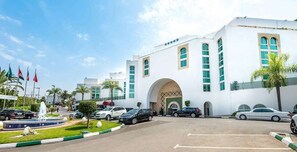 Un hotel con facciata bianca, numerose finestre e un arco centrale.