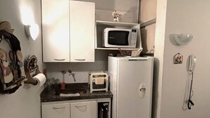 A compact kitchen with white cabinets, a microwave, a toaster, and a refrigerator. - Ap Copacabana 200m da praia – CP4 (Rio de Janeiro)