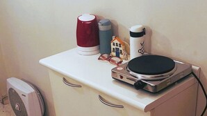 A kitchenette with a white countertop, a small fan, a mop, and a few kitchen items. - Ap Copacabana 200m da praia – CP4 (Rio de Janeiro)