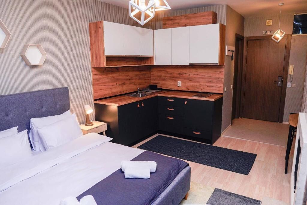 Una habitación de hotel compacta con cama, kitchenette pequeño y baño.