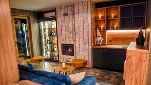 A cozy living area with a fireplace, a sofa, a coffee table, and a bookshelf. - BOUTIQUE Hotel Entry E (Bansko)
