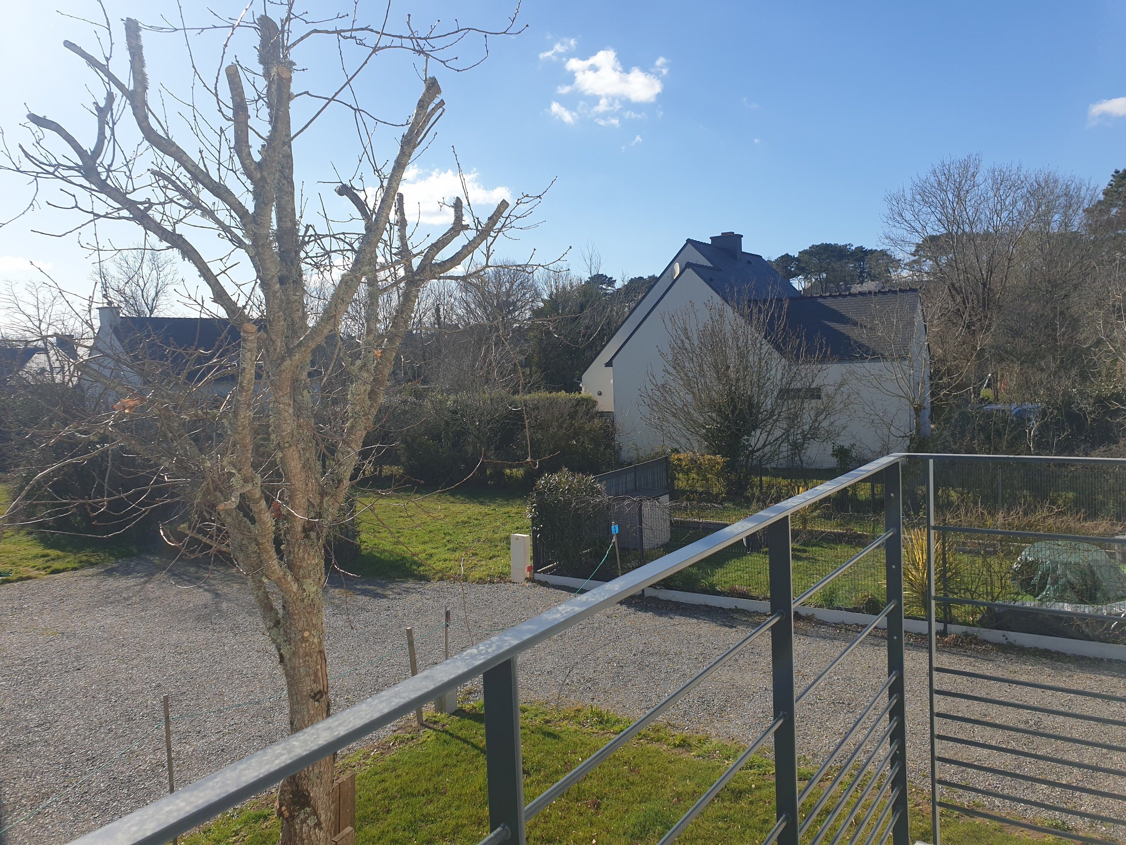 Ein Wohngebiet mit einem Haus, einem Baum und einem Schotterweg.