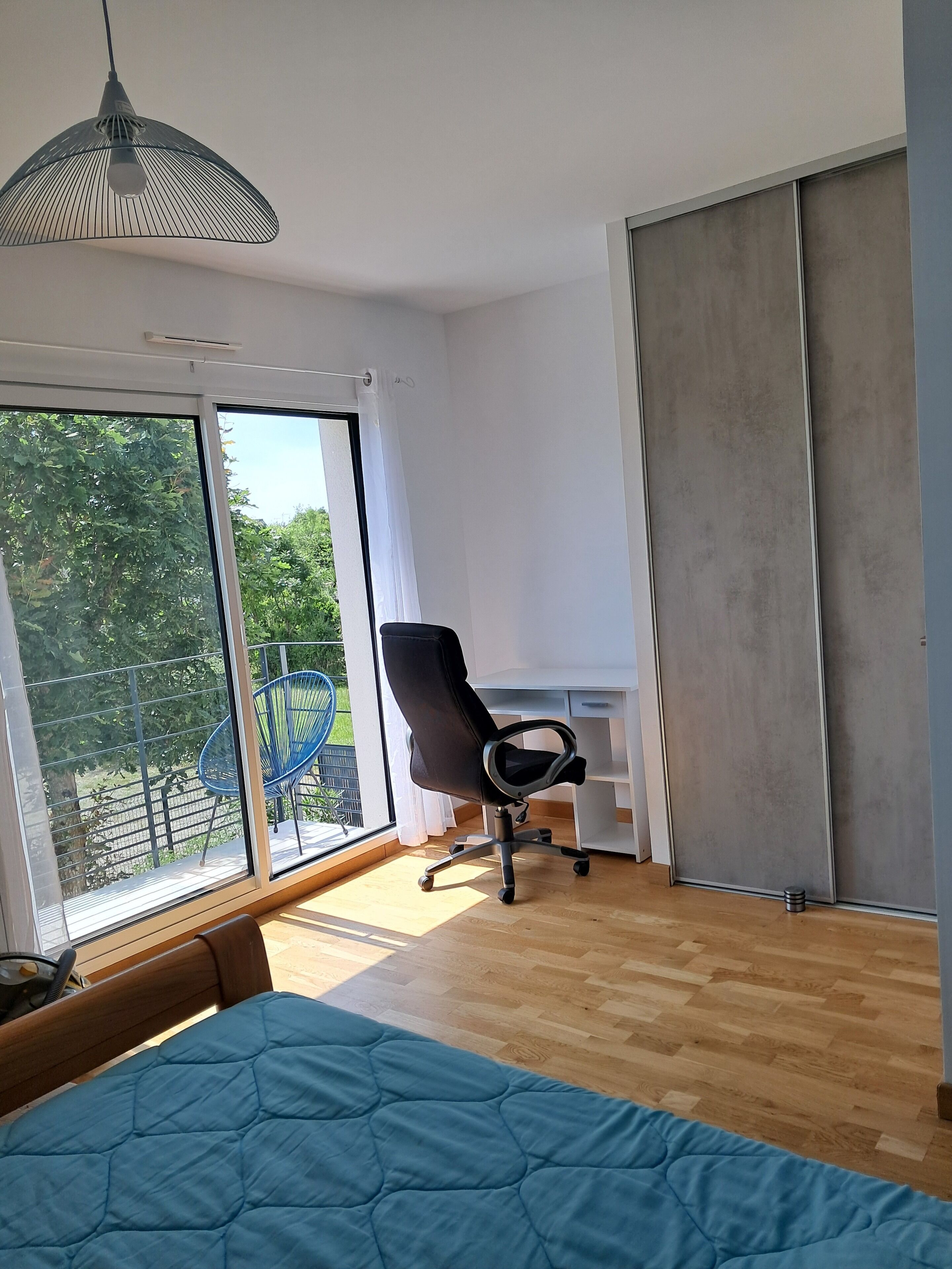A modern bedroom with a large bed, a desk, and a chair.