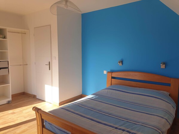 Ein Schlafzimmer mit einem hölzernen Bett, einer blauen Wand und einem weißen Kleiderschrank.