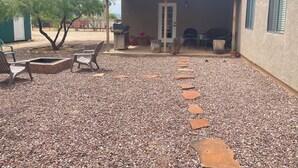 A covered outdoor patio with a barbecue area, seating, and a gravel path leading to a building. - Desert Ranch Home + 3 Horse stalls. Views of the Rincon Mountains (Tucson)