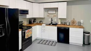 A modern kitchen with white cabinets, a black refrigerator, a wooden countertop, and a dishwasher. - Desert Ranch Home + 3 Horse stalls. Views of the Rincon Mountains (Tucson)