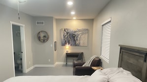 A bedroom with a bed, a desk, a chair, and a painting on the wall. - Desert Ranch Home + 3 Horse stalls. Views of the Rincon Mountains (Tucson)