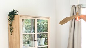 Een eetruimte met een ronde tafel, twee houten stoelen, een geweven vloerkleed, een kast met glazen deuren en een hanglamp.