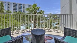 Ein Balkon mit Korbmöbeln und Blick auf einen Pool und Palmen.