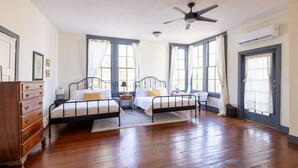 A bedroom with two beds, wooden floors, a ceiling fan, and large windows with curtains. - The Downtown Abbey- The Great Hall (San Marcos)