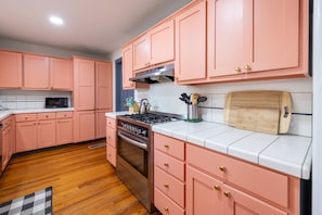 Une cuisine avec des meubles de rangement roses, une cuisinière et un four à micro-ondes.