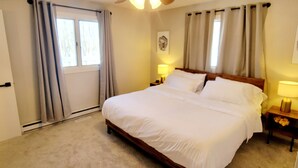 Une chambre à coucher avec un grand lit, un ventilateur de plafond et deux lampes de chevet.